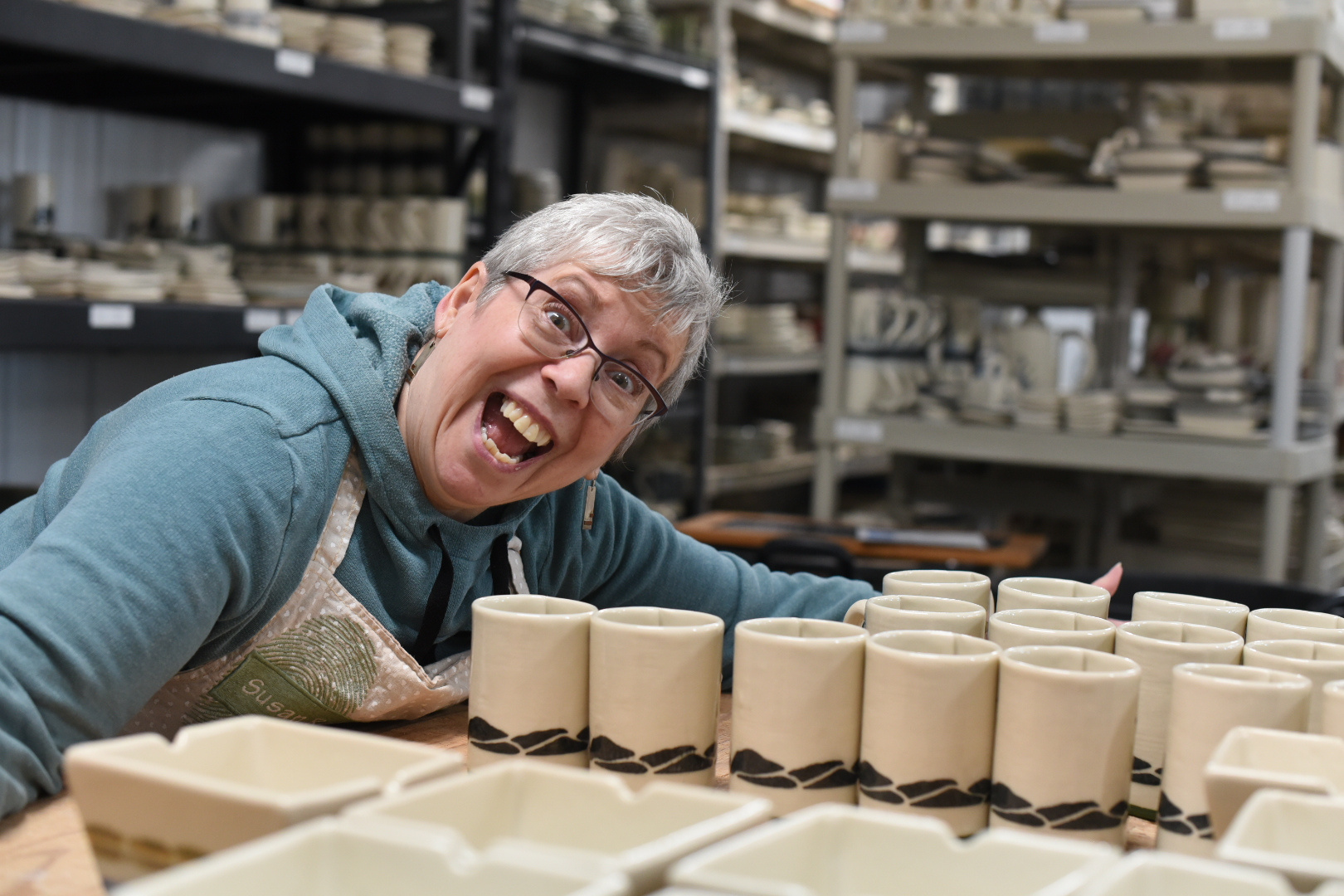 Translucent photo of Saskatchewan potter Susan Robertson smiling near some of her work
